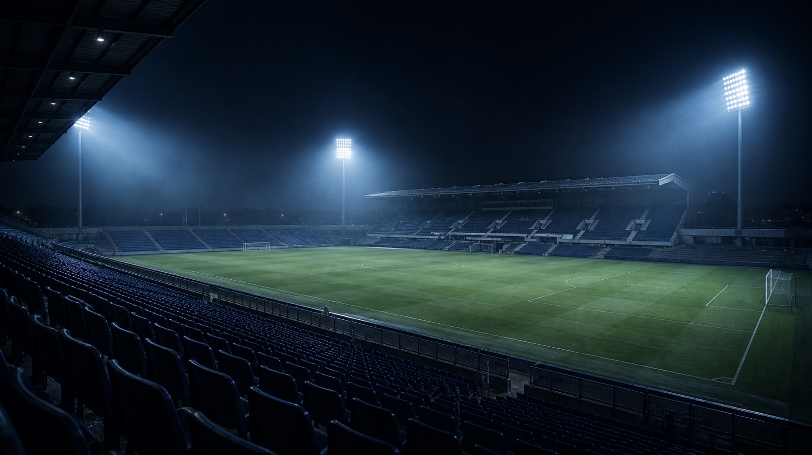 An illuminated football stadium at night under spotlights.